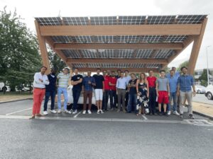 Un gruppo di colleghi sotto una pensilina fotovoltaica.