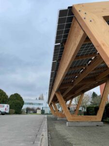 Una lunga pensilina fotovoltaica su un parcheggio in calcestruzzo.