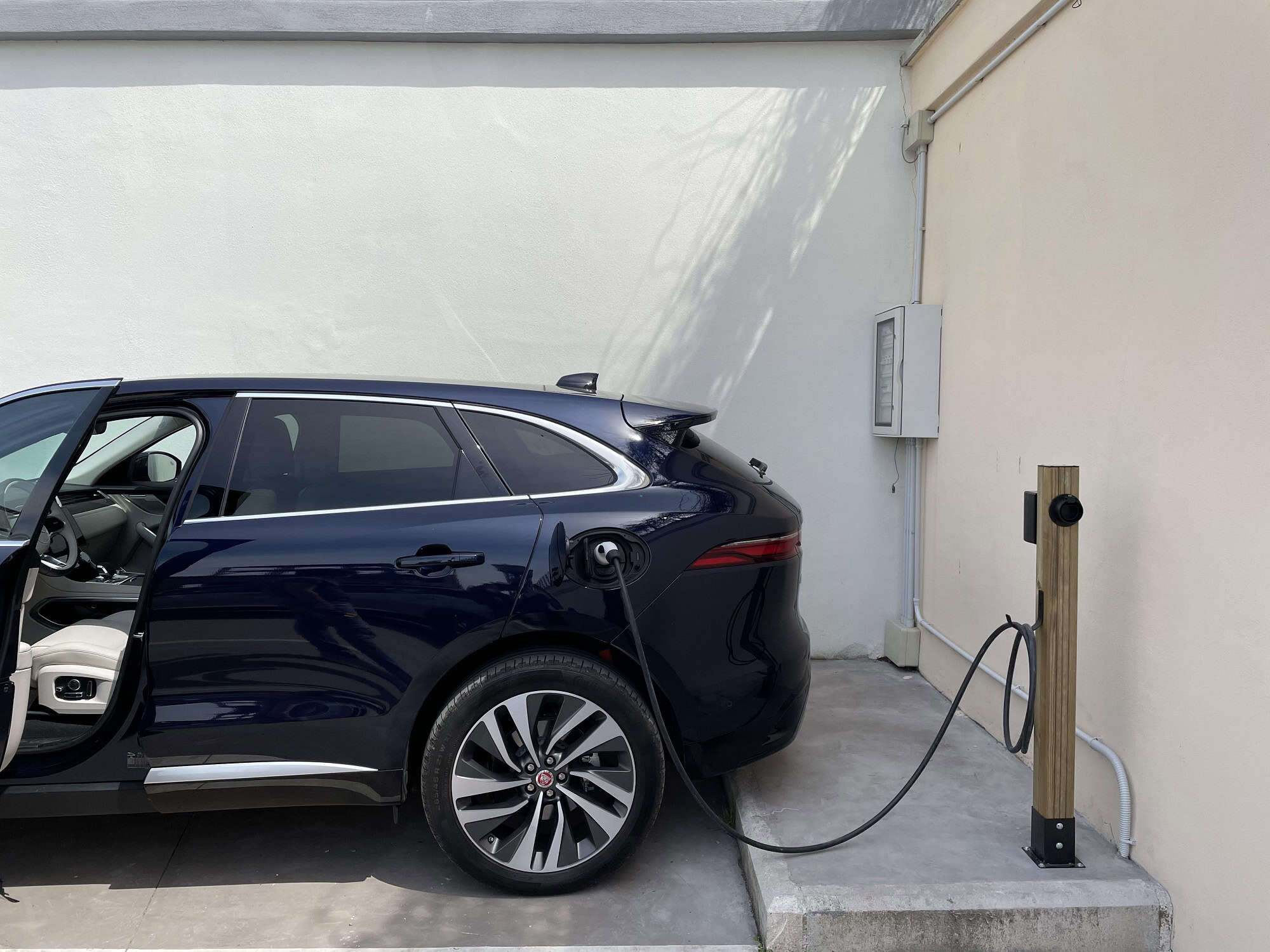 Un'auto elettrica in carica davanti a un muro bianco.
