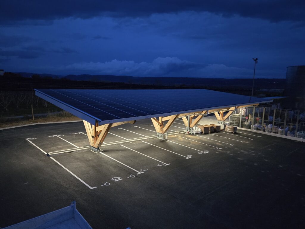 Una pensilina fotovoltaica in legno con illuminazione.